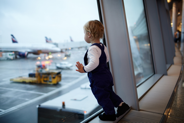 barn som tittar ut genom fönstret på en flygplats